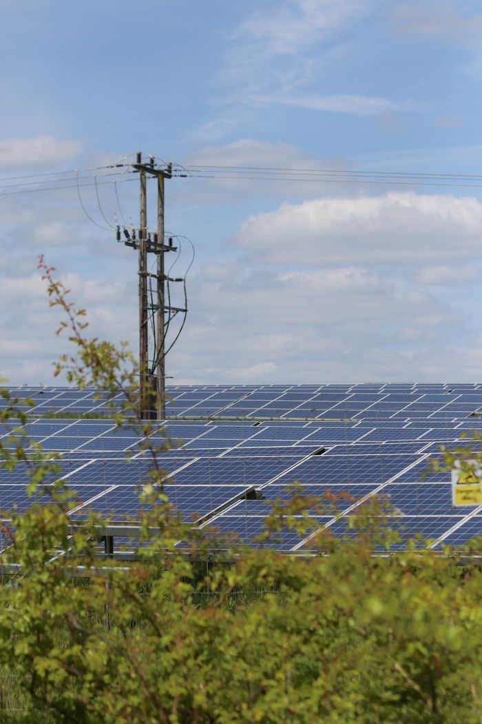 gallery-6 Solar panels in a rural area with power lines, illustrating renewable energy integration.