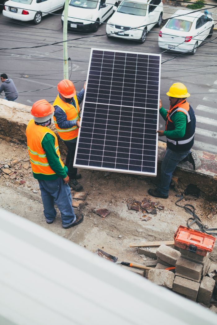 gallery-2 Workers in safety gear installing a solar panel outdoors.