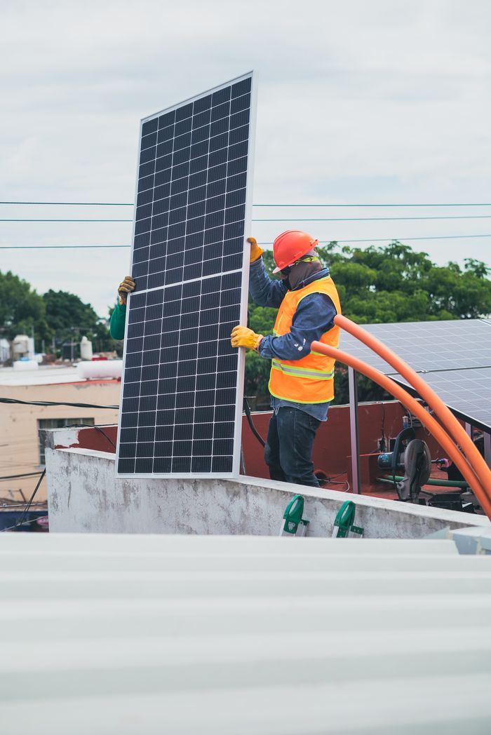 services-01 A technician in safety gear installs a solar panel on a rooftop, promoting renewable energy.
