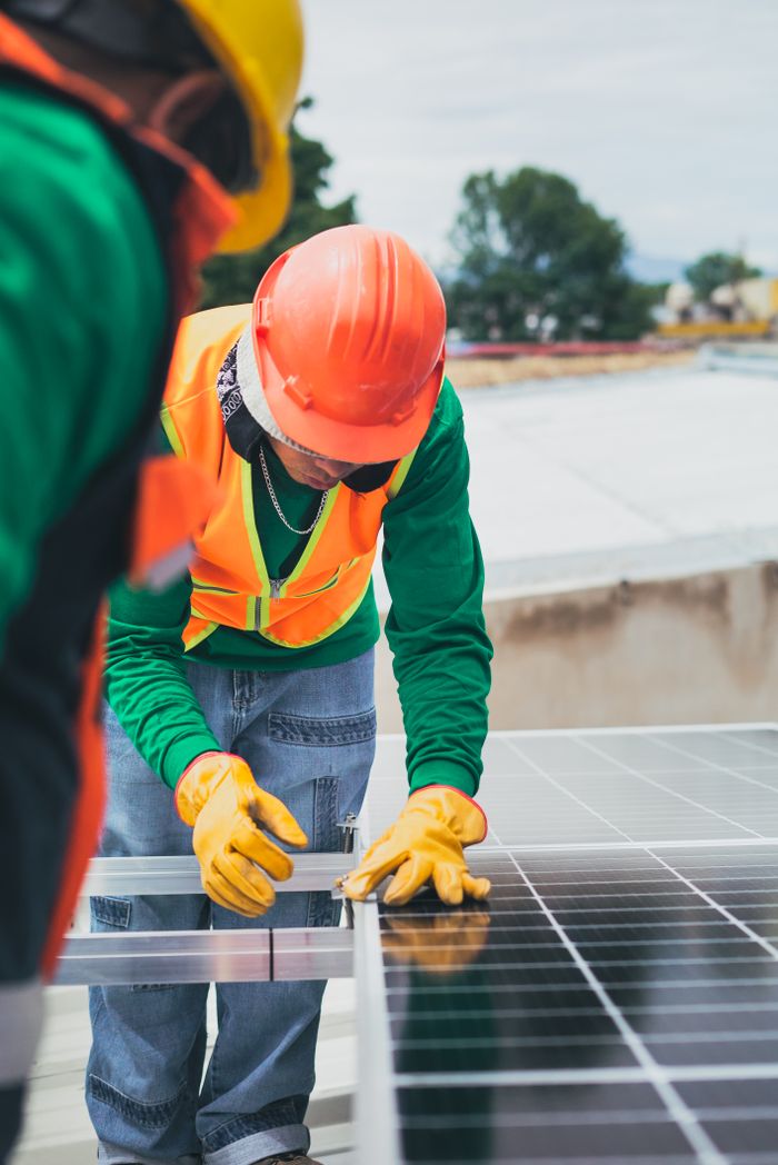 gallery-5 Worker in safety gear installing solar panels on a rooftop.